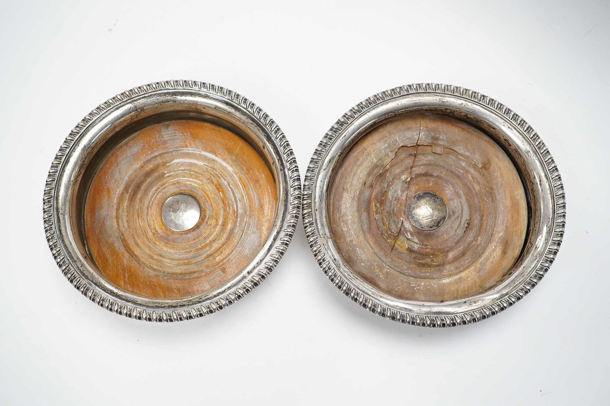 A pair of George III silver wine coasters, by John Roberts & Co, with gadrooned borders and turned wooden bases, Sheffield, 1810, diameter 15.9cm. Condition - poor